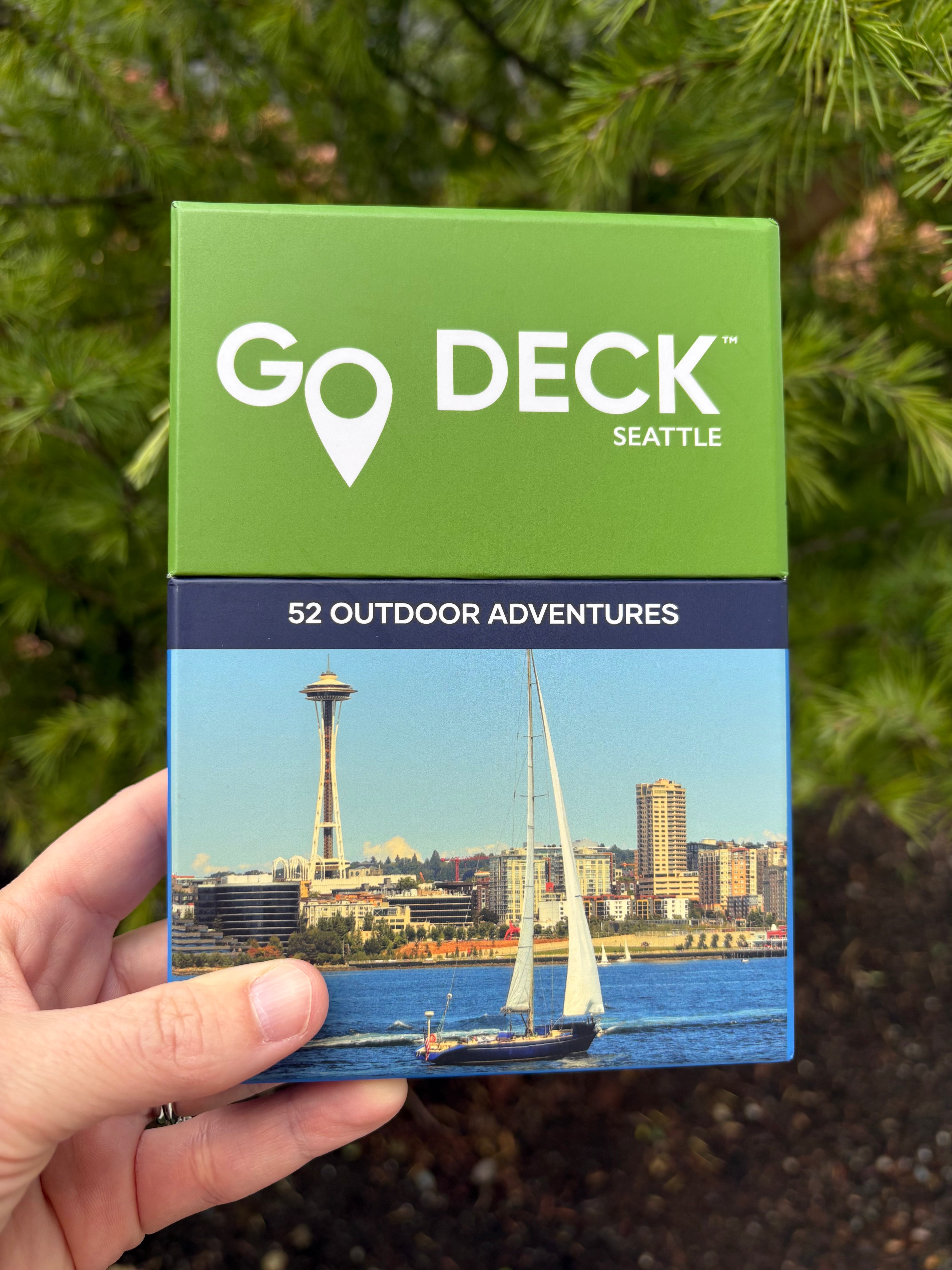 Go Deck Seattle card deck held in front of a tree